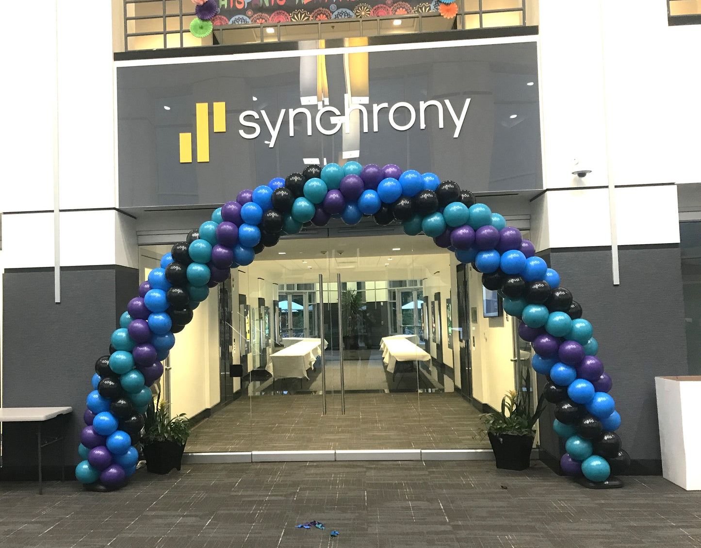 large purple, blue and black balloon arch over glass doors at synchrony financial services