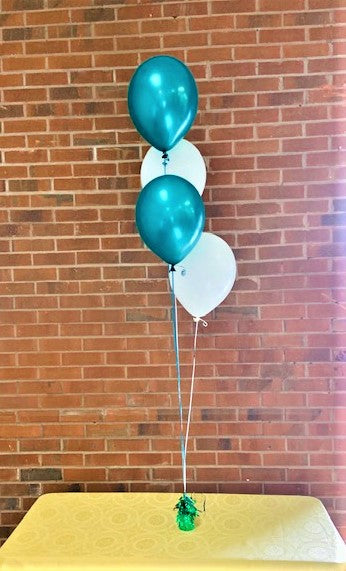 balloon centerpiece of 4 helium party balloons white and green and on a table top
