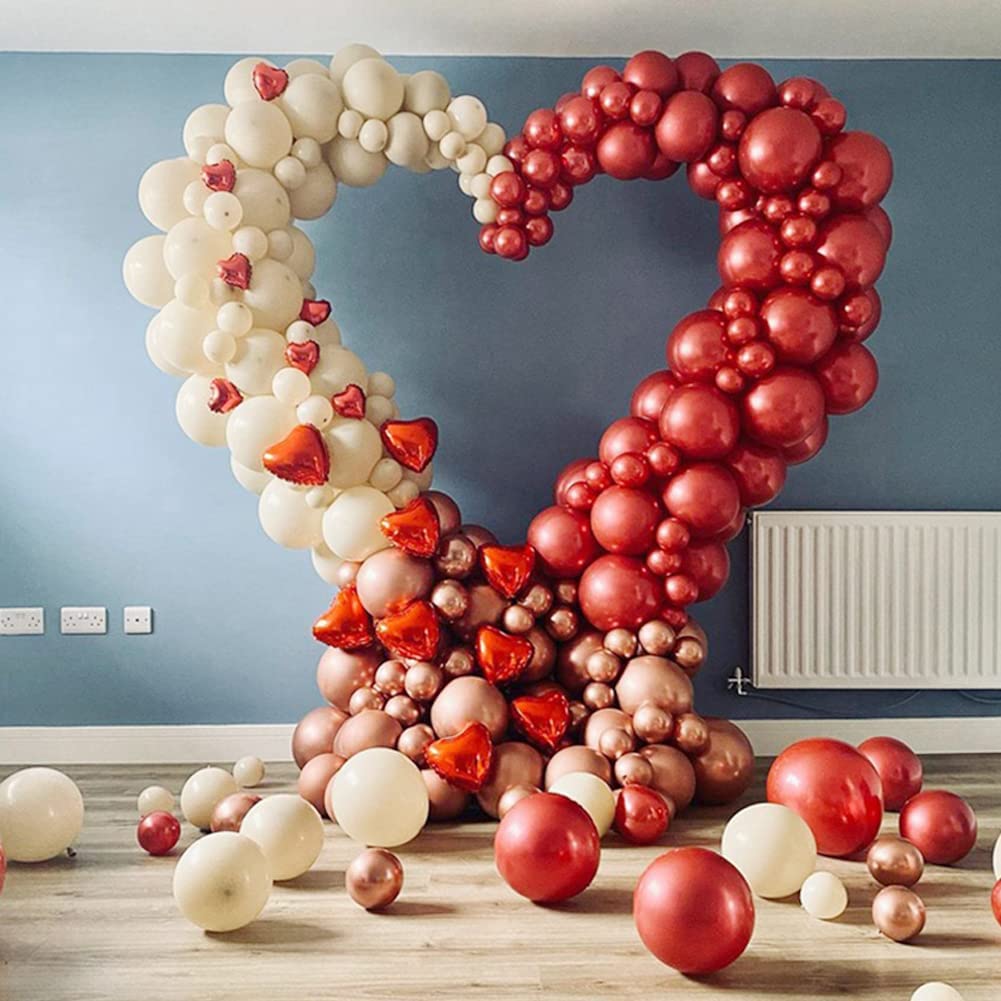 An large organic open heart-shaped balloon sculpture in red, white, and pink with a variety of balloons spread around.