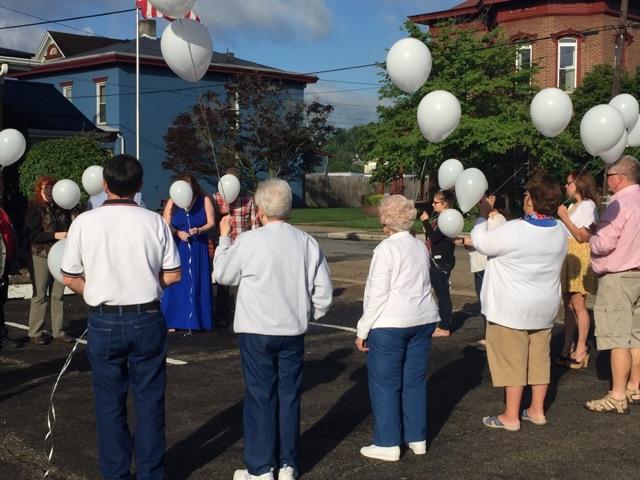 people standing holding white balloons for release