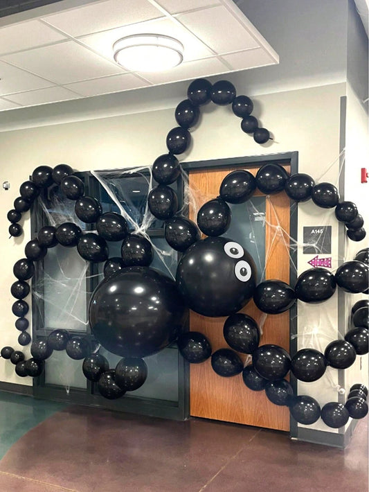 Black balloon spider decoration on a door in an indoor setting