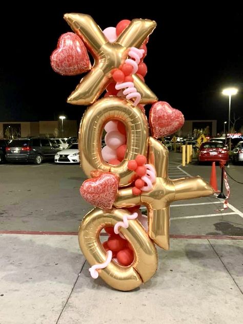 A vertical balloon column featuring  'XOXO' made out of gold letter balloons, accented with red and pink heart-shaped balloons interspersed.