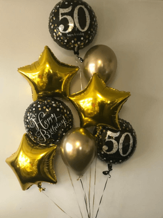A bouquet of balloons including gold stars, black balloons with '50' printed on them, and chrome balloons, all tied together with a weight at the bottom.